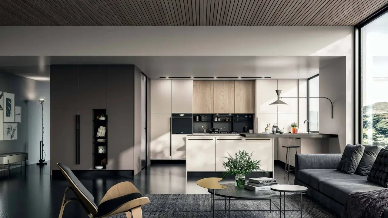 Un elegante appartamento open space moderno con cucina a vista, zona living con divano grigio e poltrona di design.