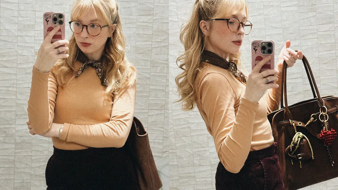 Sandra Beijer blogg: En kvinna med glasögon och ljusblont hår tar en selfie med sin telefon. Hon bär en orange tröja, mörk kjol och en brun väska.