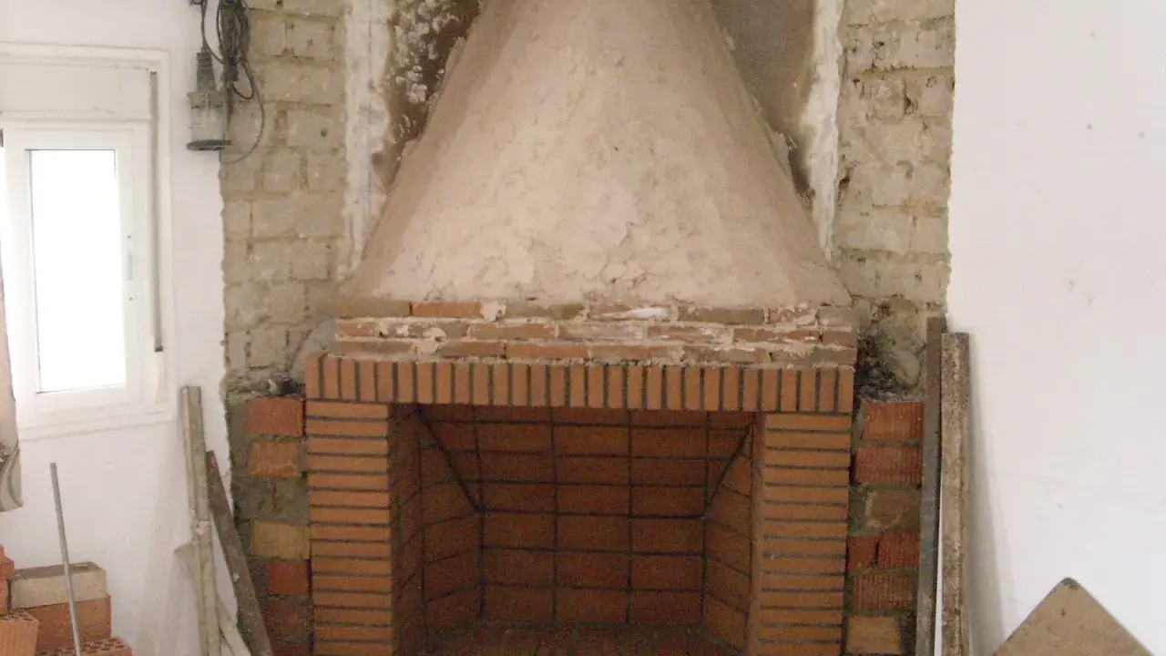 Construcción de chimenea de obra. El hogar de ladrillo y la campana cónica de cemento están en proceso. Aprende como hacer una chimenea de obra que no haga humo.