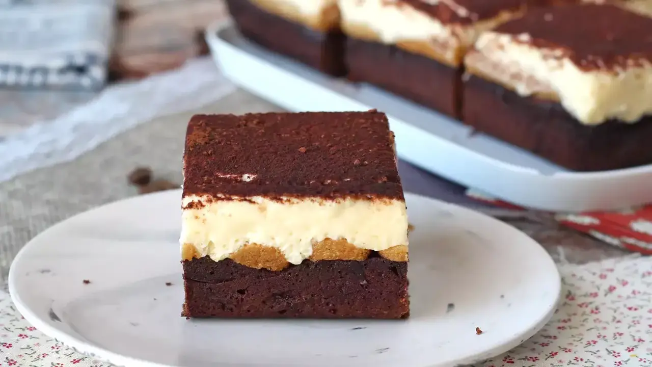 Pyszny deser tiramisu przepis. Warstwy czekoladowego ciasta, biszkoptów i kremu, posypane kakao.