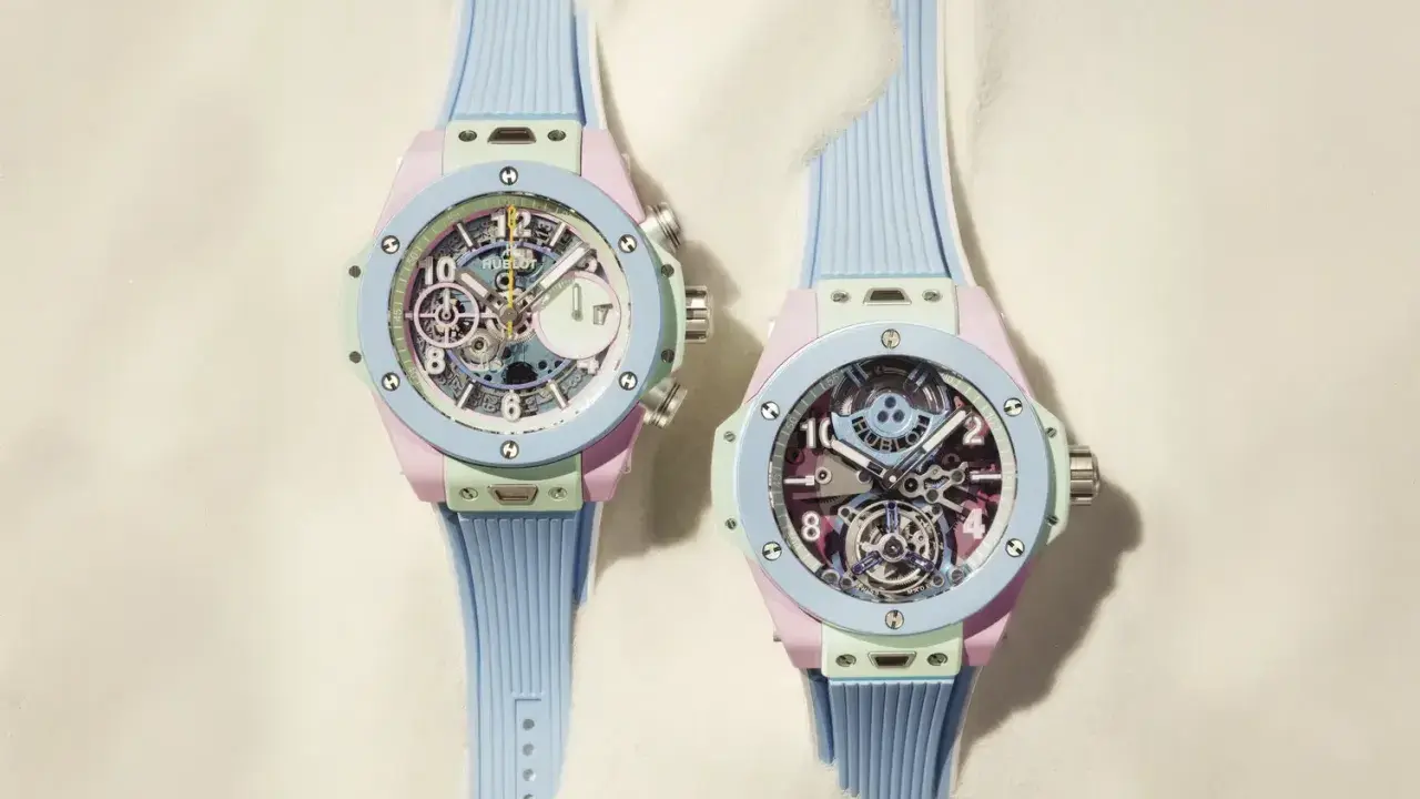 Due orologi con cinturino azzurro e cassa color pastello, con un intricato calibro di manifattura visibile sul quadrante.