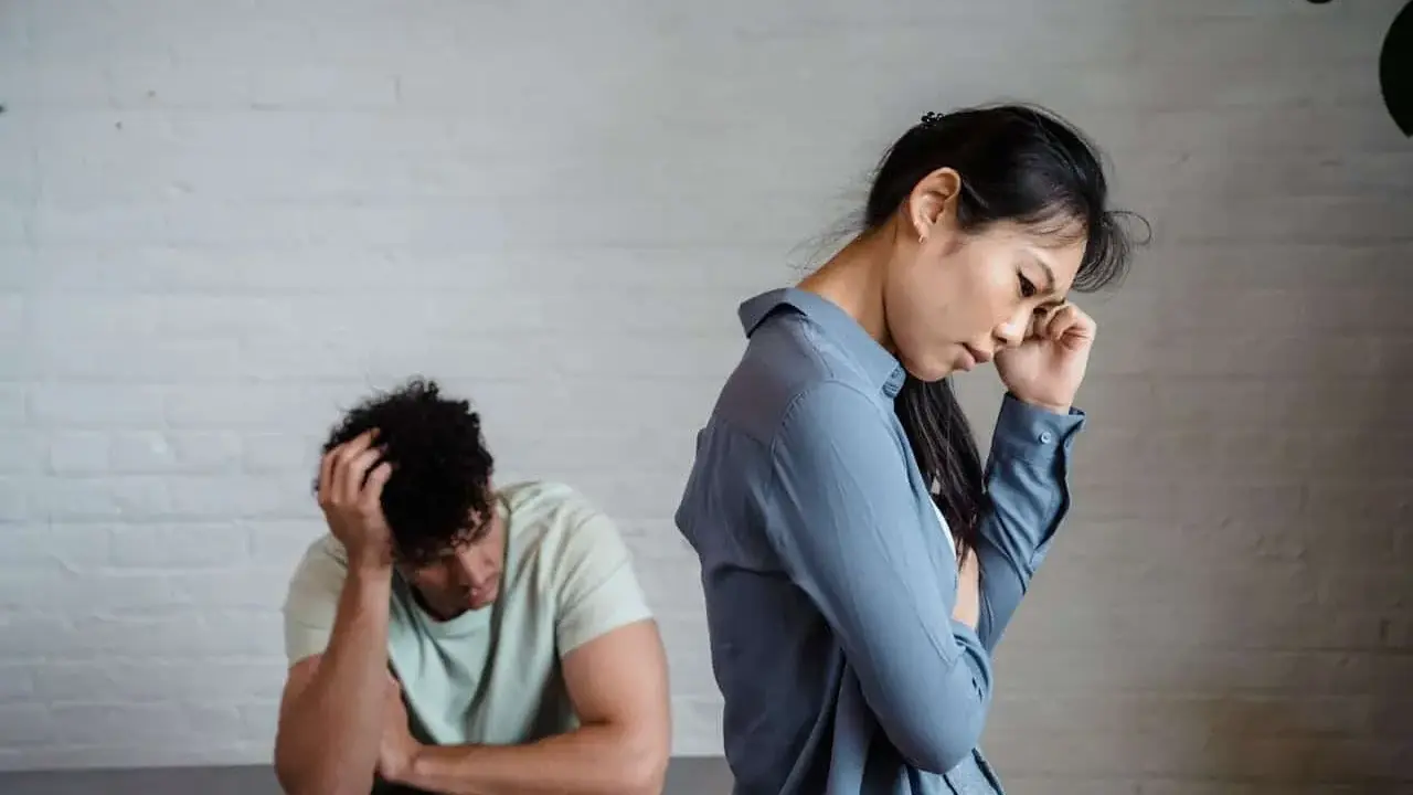 Pareja con expresiones de desánimo, uno con la mano en la cabeza, el otro pensativo. Un reflejo del refuerzo intermitente en la pareja.
