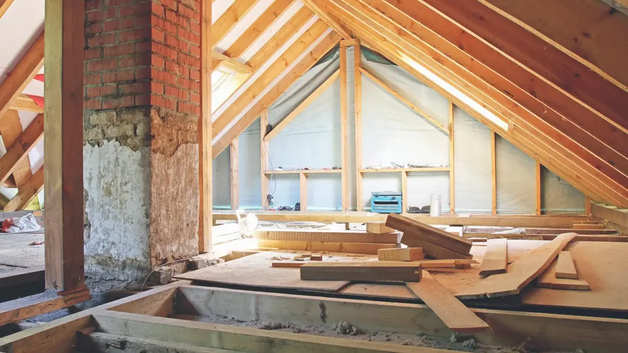 Aménagement des combles : début de la création d'un plancher avec des poutres en bois et des matériaux de construction.