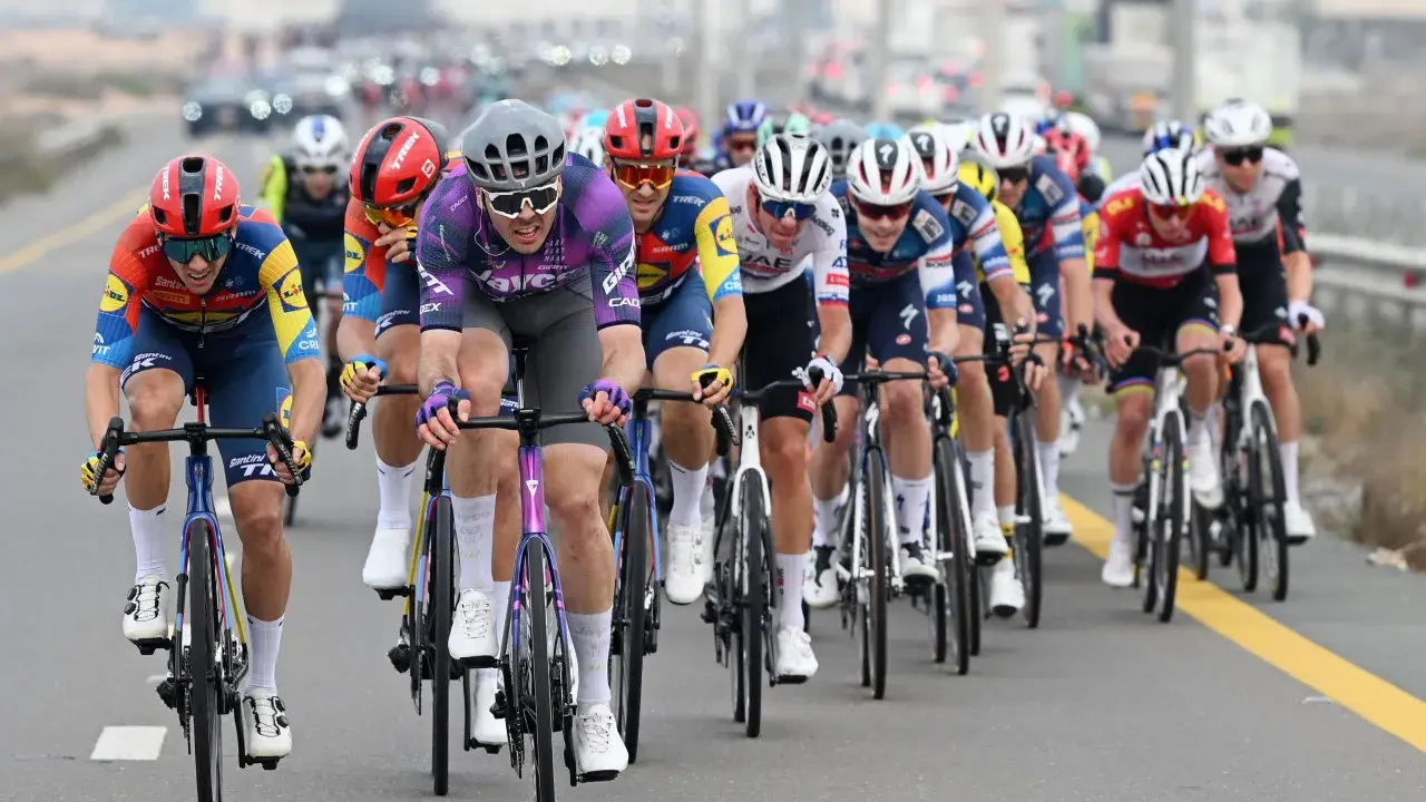 Max Walscheid im violetten Trikot kämpft sich mit anderen Radfahrern durch ein Rennen.