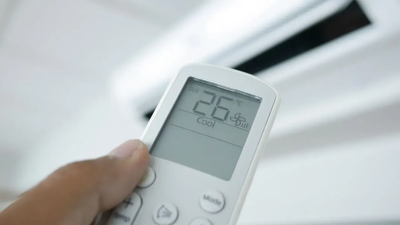 Mando a distancia de aire acondicionado mostrando 26°C en modo "Cool". El modo "Dry" deshumidifica el aire.
