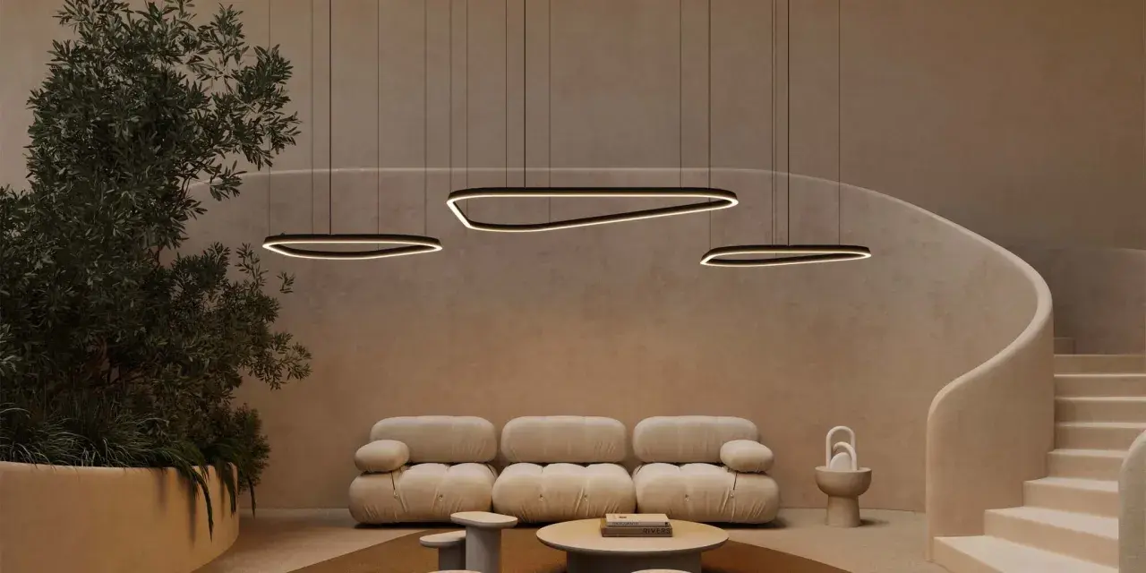 Un salon moderne avec un plafond cathédrale, des suspensions lumineuses organiques, un canapé moelleux et un escalier incurvé.