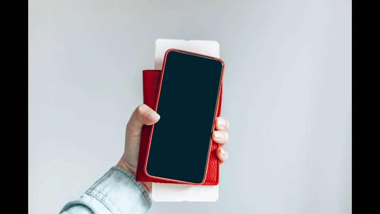 Dłoń trzyma iPhone'a w czerwonym etui. Czy iPhone jest bezpieczny? Zależy od użytkownika i jego nawyków.