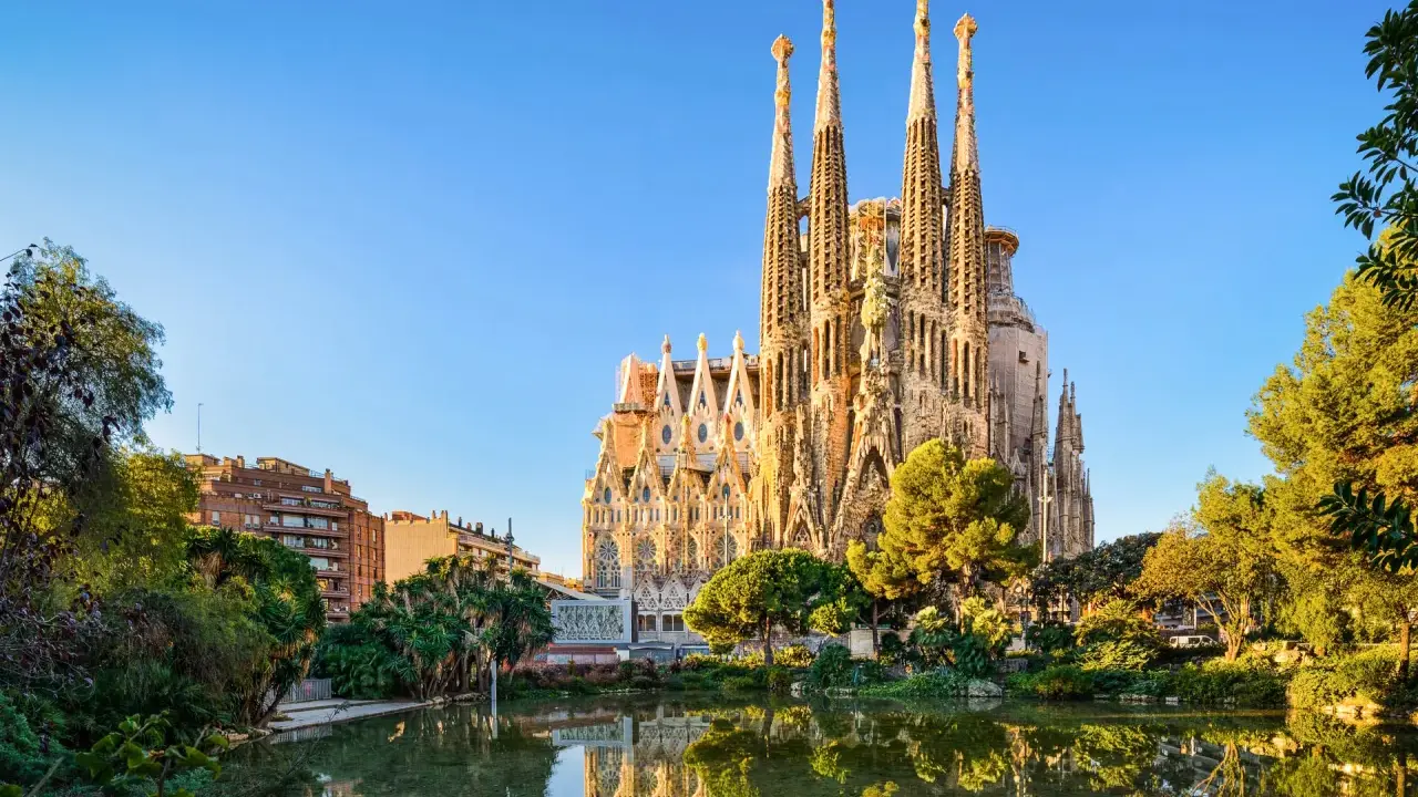 La Sagrada Familia, simbolo di **attività Barcellona**, si specchia in un laghetto circondato da verde.
