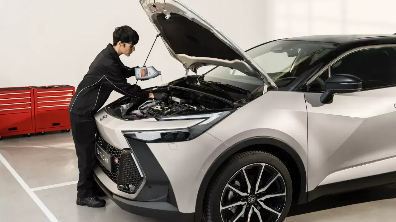 Mechanik wlewa olej do silnika Toyoty. Sprawdź nasz **toyota serwis gwarancyjny cennik** i umów wizytę.