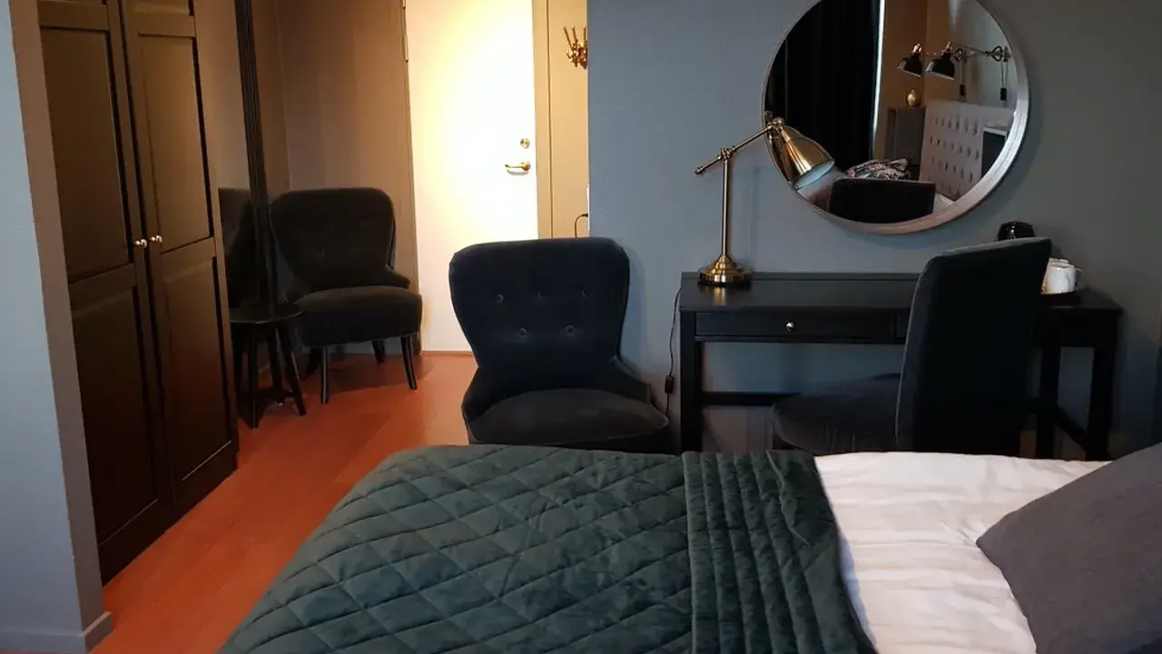 Ett modernt rum på Haparanda Stadshotell med en stor säng, skrivbord, spegel och bekväma fåtöljer.