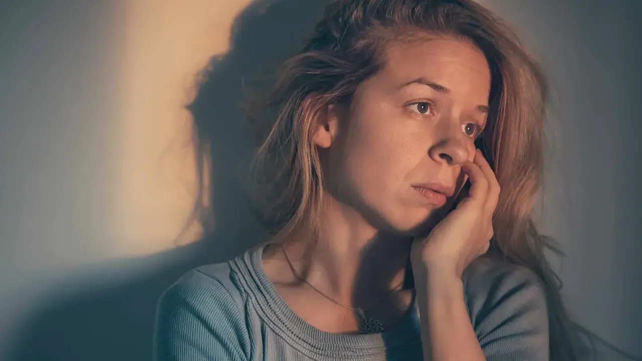 Une femme songeuse, le regard perdu, se demande : "suis je sous l'emprise d'un manipulateur test ?" Son visage exprime le doute et l'inquiétude.