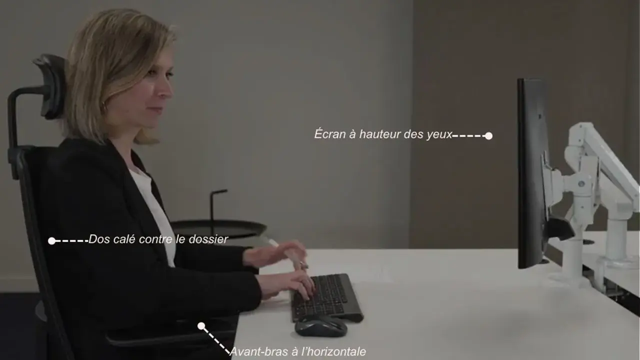 Une femme assise, respectant la règle ergonomique : dos calé, avant-bras à l'horizontale, écran à hauteur des yeux.