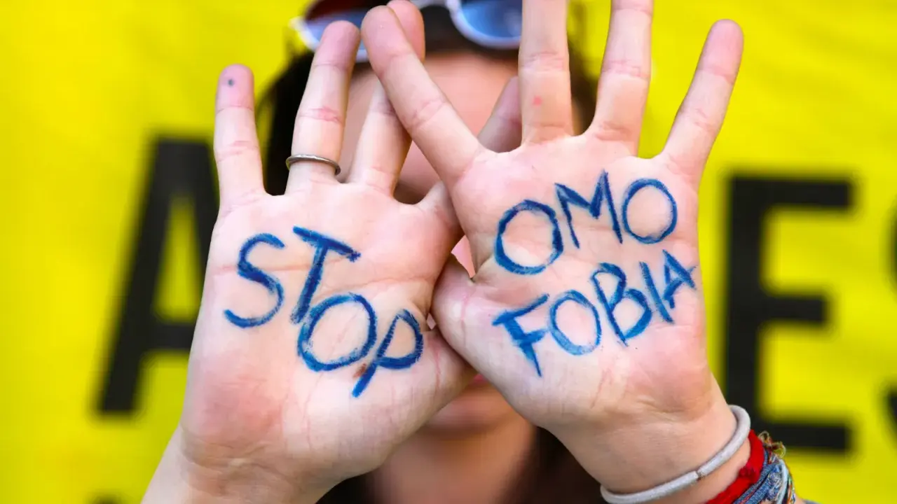 Mani con scritto "STOP OMOSESSUALITÀ" in blu, un messaggio contro il bullismo omofobico.