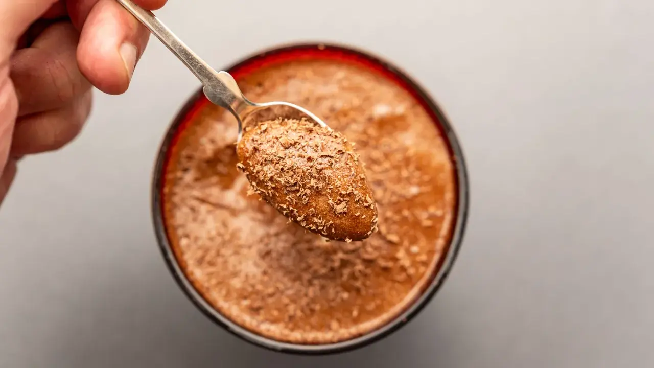 Ein Löffel mit Schokostückchen auf einer cremigen Mousse au Chocolat. Das Originalrezept für puren Genuss.