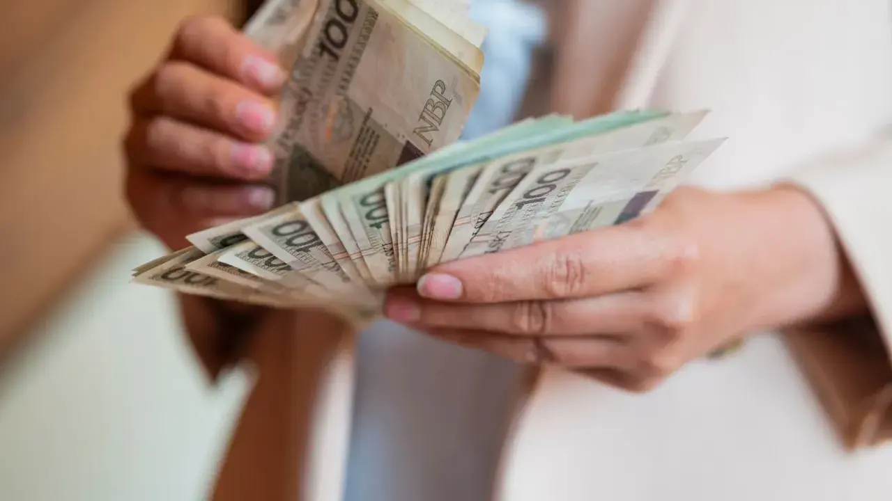 Dłonie liczą banknoty 100 zł. To może być świadczenie pielęgnacyjne, które pomaga w codziennym życiu.