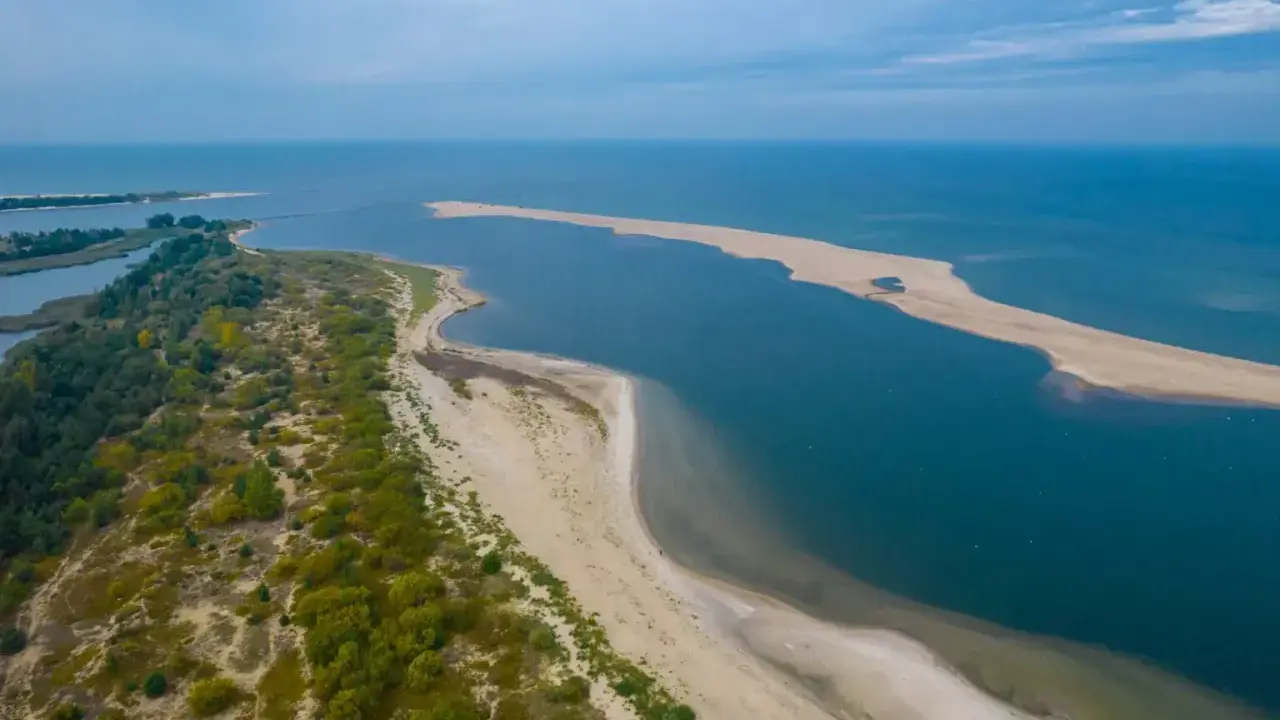 Piękny **urlop w Polsce** nad morzem. Piaszczysta plaża, zieleń i błękit wody tworzą malowniczy krajobraz.
