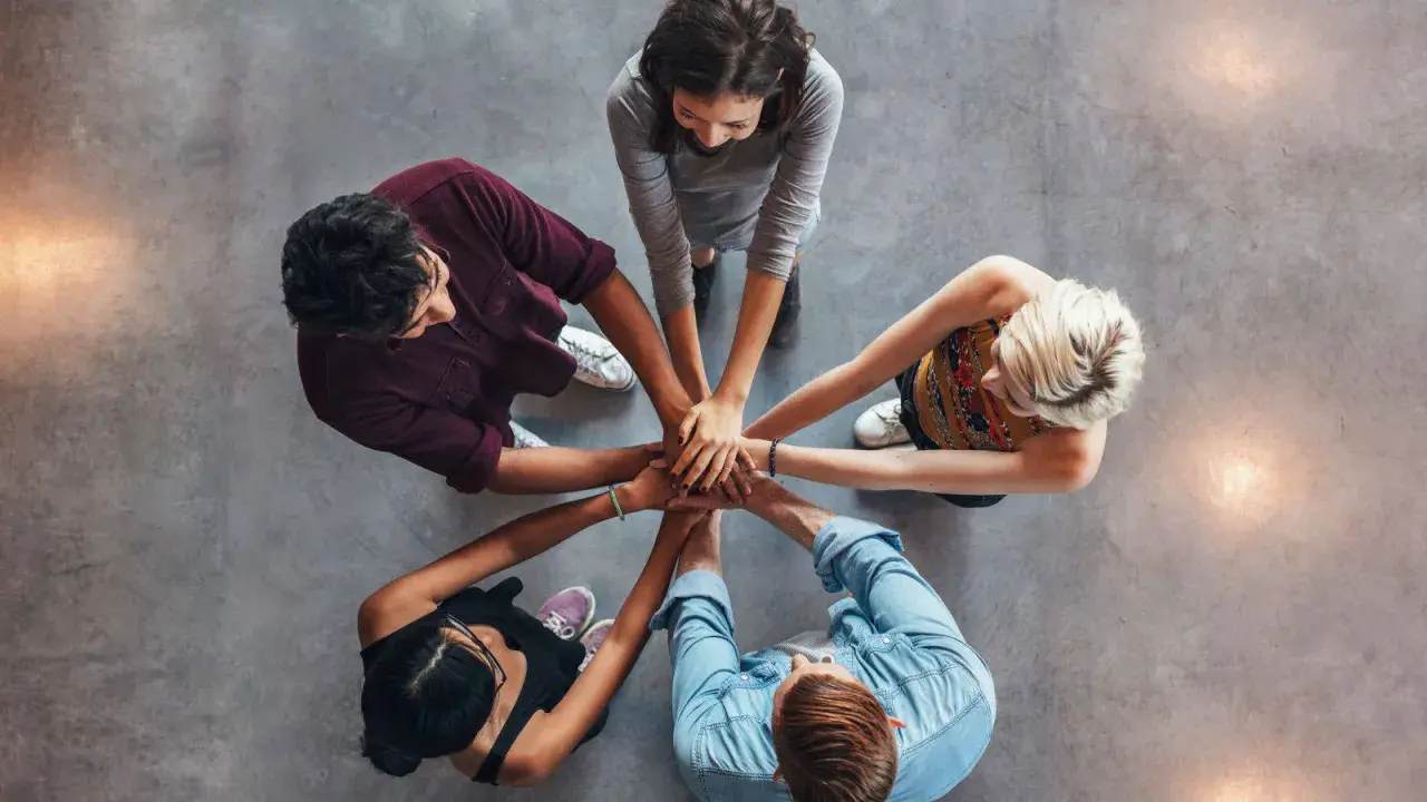 Un gruppo di persone unisce le mani, un'immagine che incarna la social definizione di unità e collaborazione.