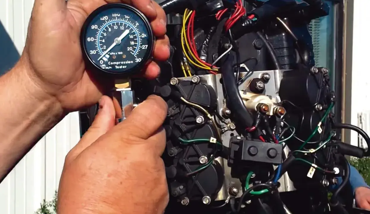 Mains d'un mécanicien utilisant un testeur de compression sur un moteur hors-bord. Le moteur se lance mais ne démarre pas essence.