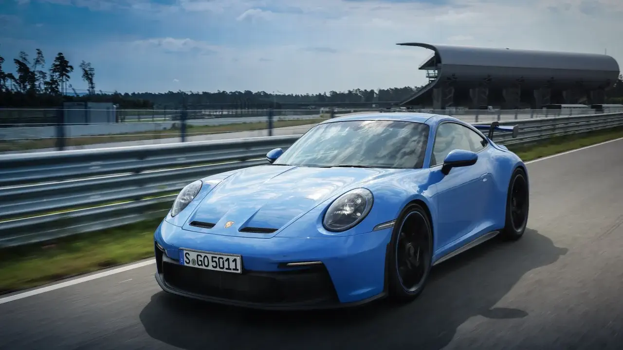 Ein blauer Porsche GT3 Rennwagen rast auf einer Rennstrecke.