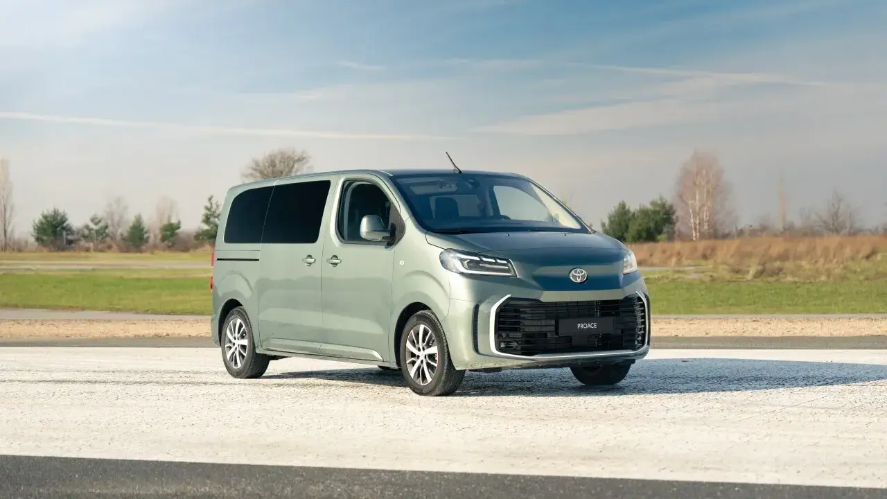 Nowy, zielony minivan Toyota Proace Verso na tle nieba i pól. Idealny na rodzinne wycieczki.