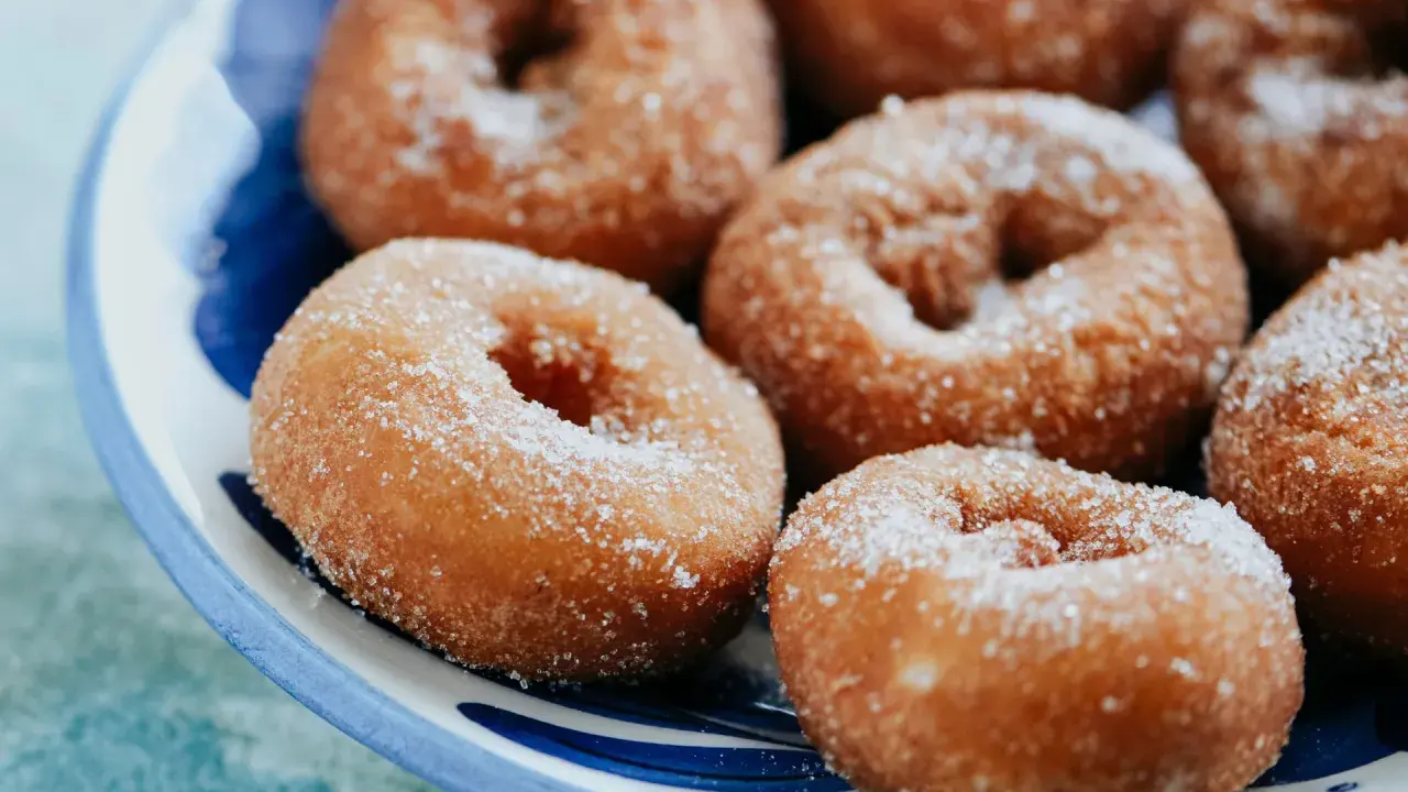 Rosquillas caseras de toda la vida, doradas y espolvoreadas con azúcar, listas para disfrutar.