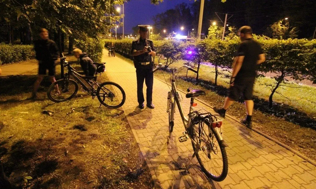 Policjant rozmawia z rowerzystą, który może stracić prawo jazdy. Nocna interwencja na ścieżce rowerowej.