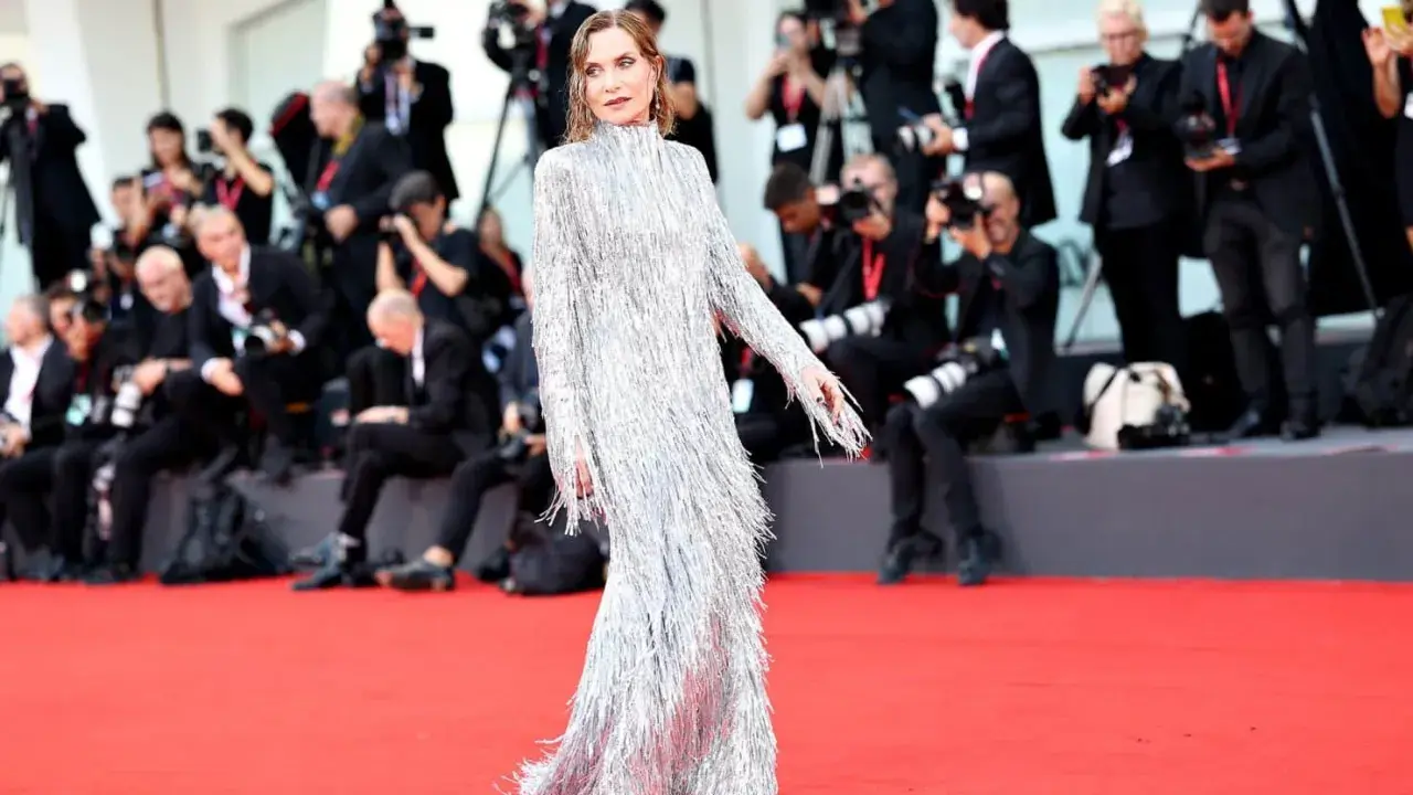 Isabelle Huppert, éblouissante dans sa robe argentée à franges, foule le tapis rouge de la mostra de Venise, sous le regard des photographes.