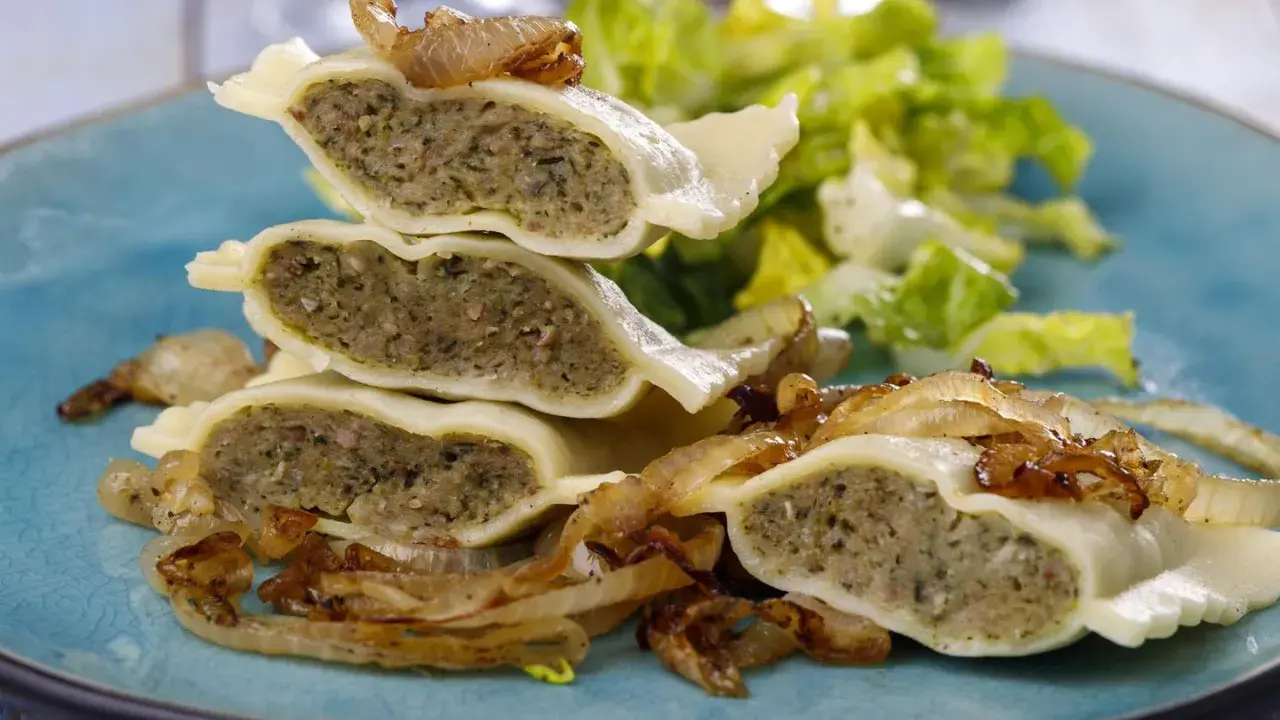 Gestapelte Maultaschen mit gebratenen Zwiebeln und Salat. Ein köstliches Maultaschen Rezept, das Appetit macht.