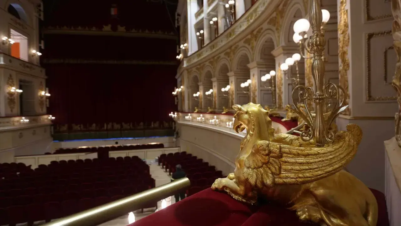 Interno del Teatro Galli di Rimini, con poltrone rosse, palchi dorati e una sfinge alata in primo piano.