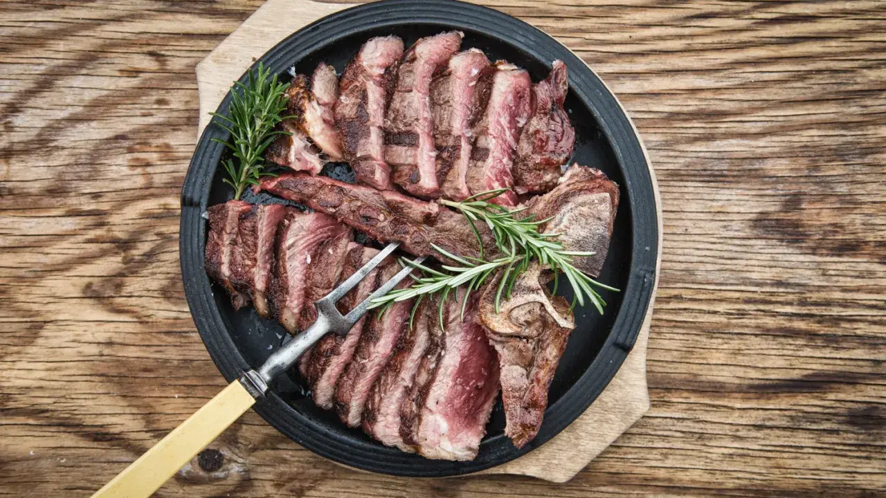 Una succulenta bistecca fiorentina affettata, guarnita con rosmarino, pronta per essere gustata.