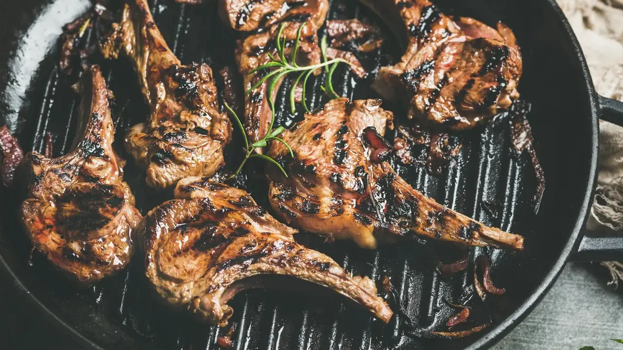 Saftige Lammkoteletts mit Grillstreifen in einer Pfanne, garniert mit Rosmarin. Perfekt zum Lamm grillen!