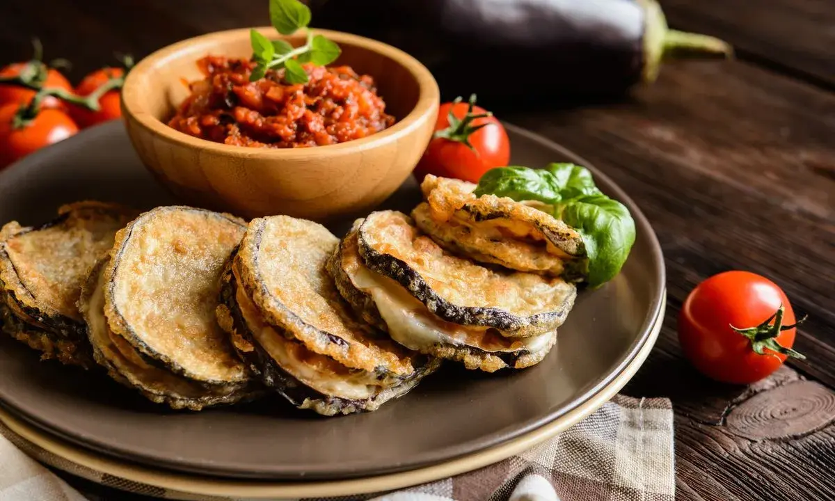 Cotolette di melanzane dorate e croccanti, servite con salsa di pomodoro e basilico fresco.