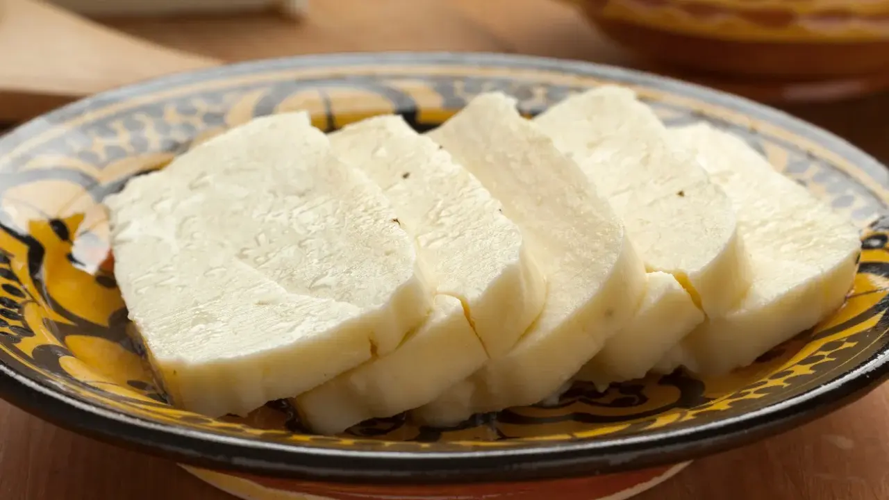 Pokrojony w plastry domowy ser halloumi na ozdobnym talerzu.