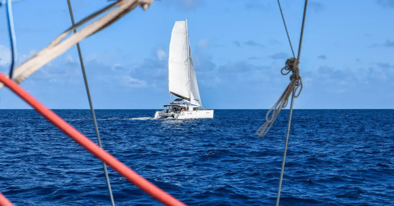 Un catamaran blanc navigue sur l'océan bleu. La durée de la traversée de l'Atlantique en bateau est longue, mais la beauté du voyage est inestimable.