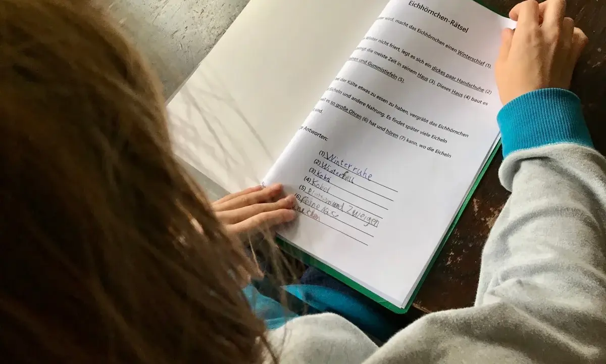 Kind löst ein Eichhörnchen-Rätsel, die Antworten sind bereits eingetragen. Eine leichte eskalation bei hausaufgaben, da die Antworten teils unleserlich sind.