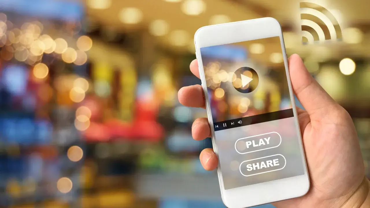 Dłoń trzyma smartfon Huawei, na ekranie którego widać interfejs odtwarzacza wideo z przyciskiem "PLAY" i "SHARE", sugerujący dostęp do treści z Google Play.
