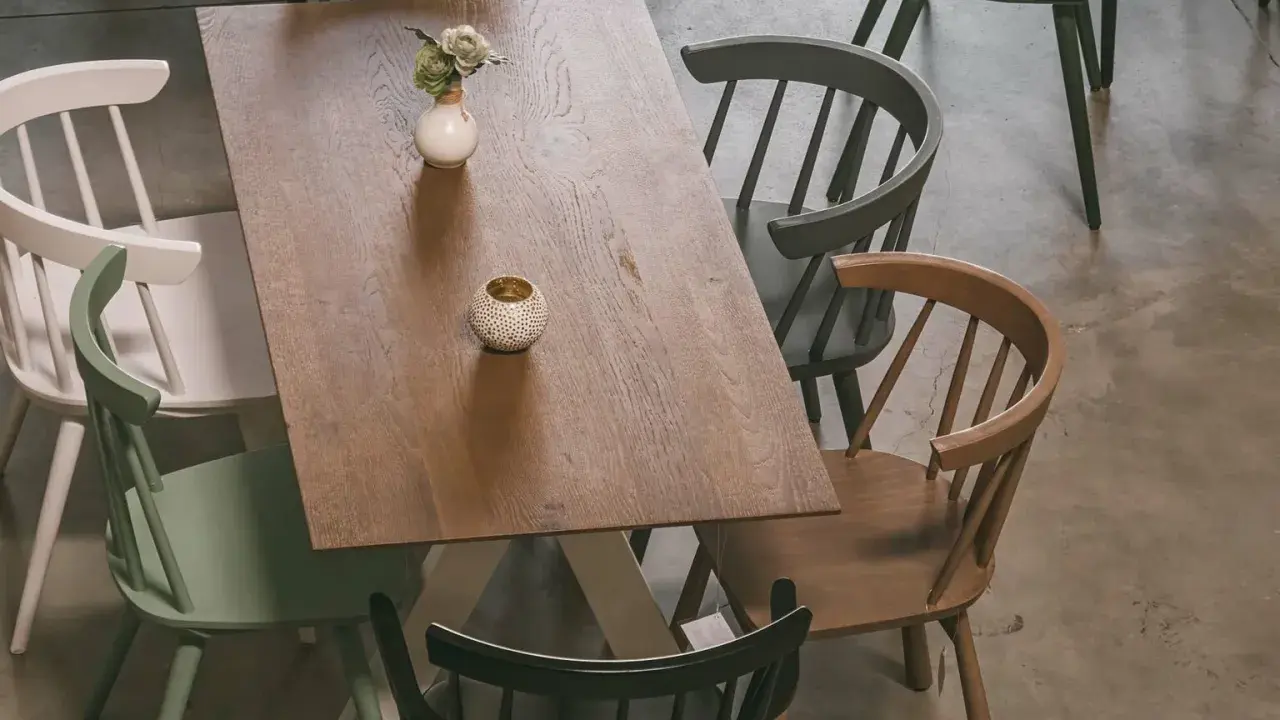 Holztisch mit bunten Stühlen und Deko-Elementen, aus der Vogelperspektive.