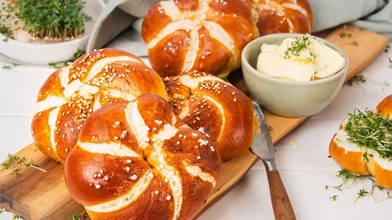 Frisch gebackene laugen knoten mit Sesam und grobem Salz, dazu Butter und Kresse.