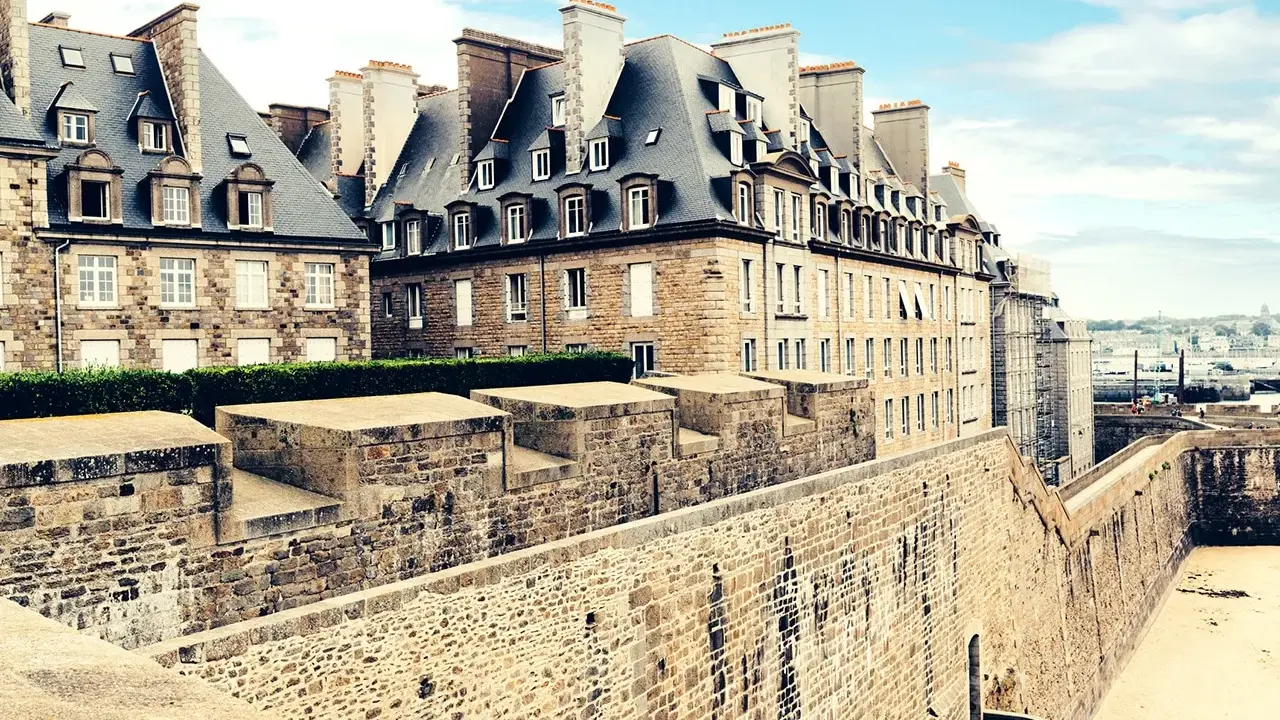 Murs de pierre de la ville fortifiée de Saint-Malo, avec des maisons bretonnes typiques et une vue sur la mer. Imaginez une pause à la taverne de Saint-Malo.