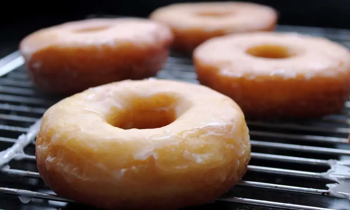 Cuatro donuts glaseados sobre una rejilla, listos para disfrutar. Una deliciosa receta de donuts caseros.