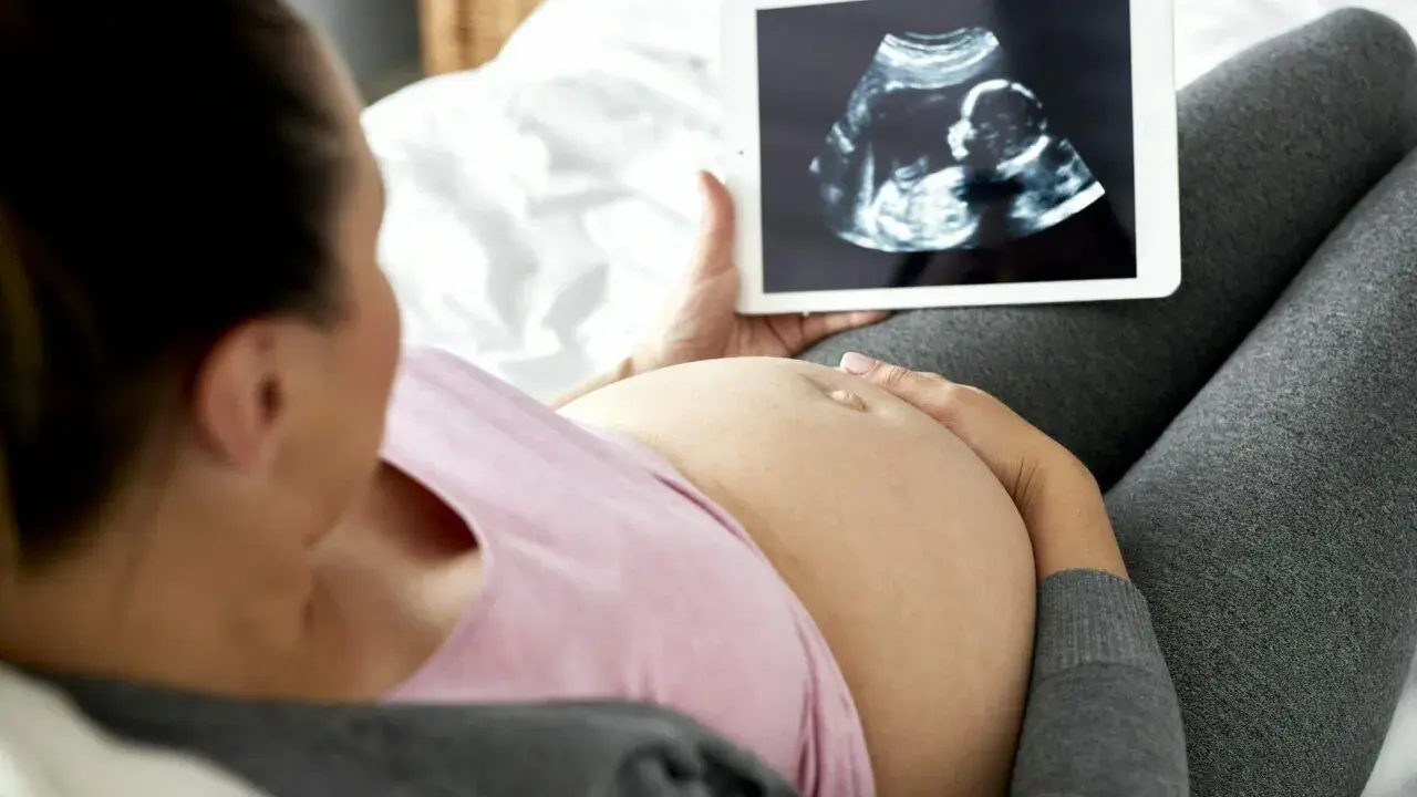 Kobieta w ciąży ogląda na tablecie zdjęcie USG. To jej badania prenatalne w 3 trymestrze.