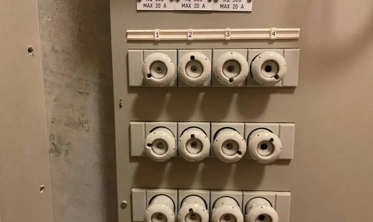 Säkringsskåp med keramikproppar, alla märkta MAX 20 A. En diskussion om prisskillnad mellan 16 A och 20 A säkringar kan uppstå.