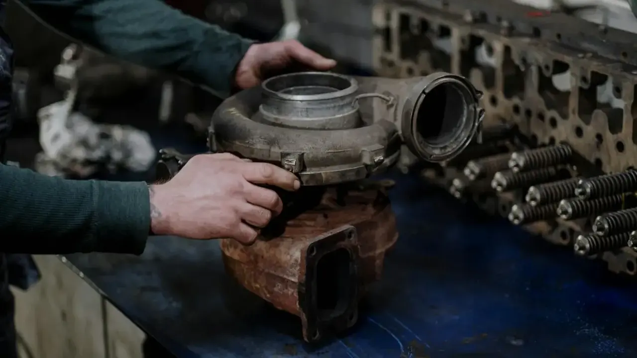 Mechanik sprawdza turbosprężarkę, przygotowując się do jej montażu.