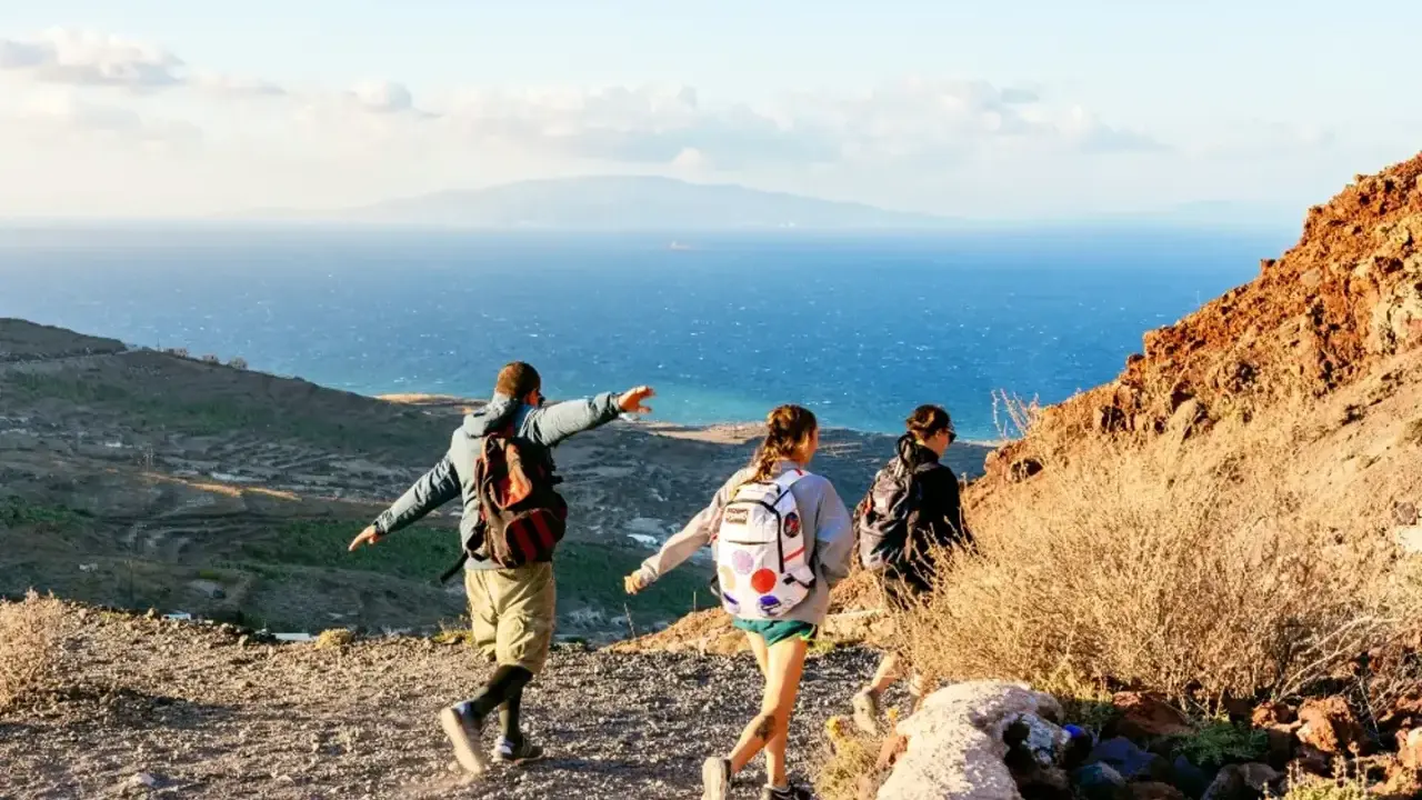 Vandrare njuter av utsikten över havet och landskapet på Santorini. En man pekar ut mot horisonten.