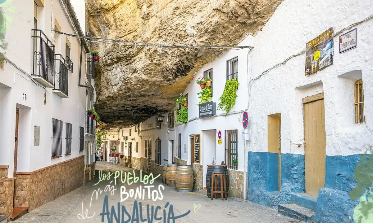 Calle bajo roca en Setenil de las Bodegas, uno de los pueblos mas bonitos de Andalucia. Casas blancas con balcones floridos y barriles de vino.