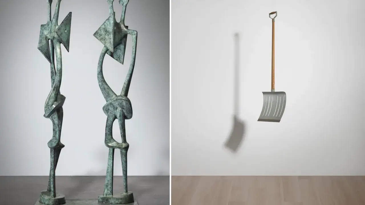 Two abstract bronze figures stand side-by-side, a modern sculpture. To the right, a metal snow shovel hangs suspended, its shadow cast on the wall.
