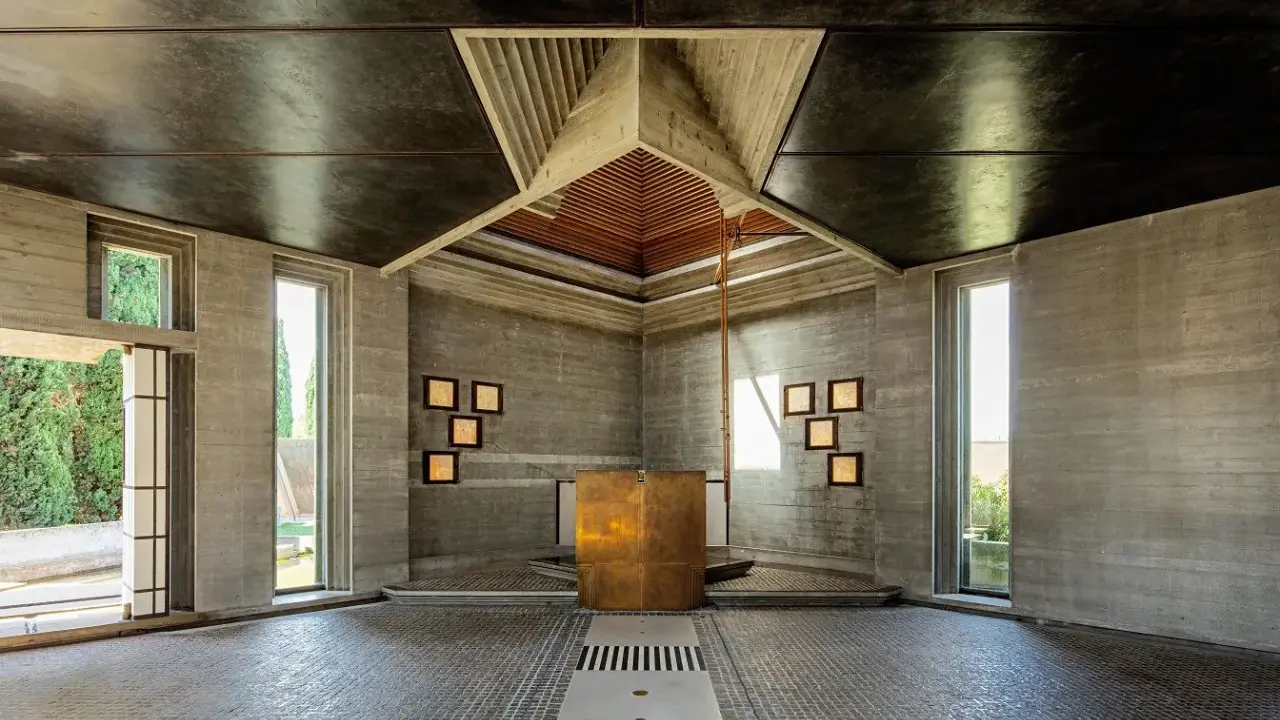 Interno moderno con altare dorato, pareti in cemento grezzo e soffitto a punta. Un esempio di architetti famosi italiani.