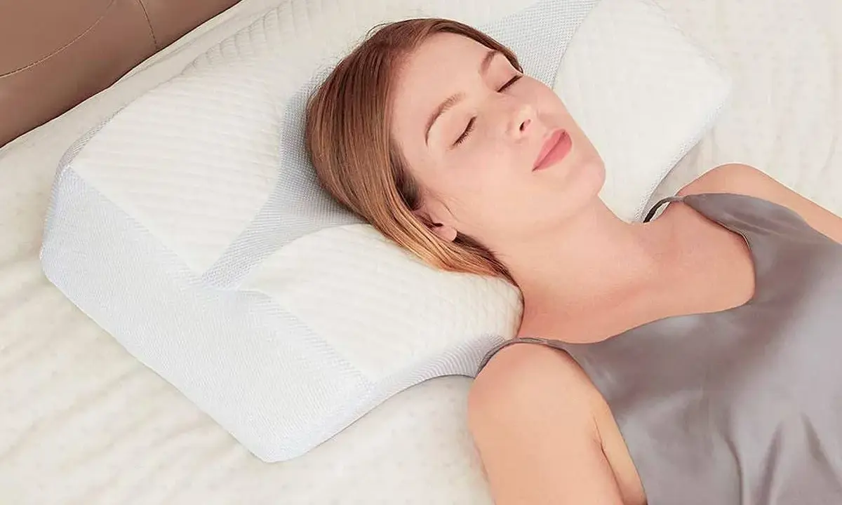 Mujer durmiendo plácidamente sobre una almohada ergonómica. Aprende como colocar la almohada correctamente para un descanso óptimo.
