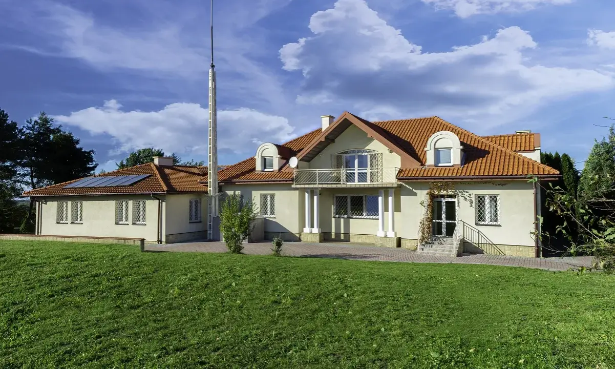 Nowy początek w ośrodku terapii uzależnień i depresji. Dom z czerwonym dachem, otoczony zielenią, zaprasza do spokoju i regeneracji.