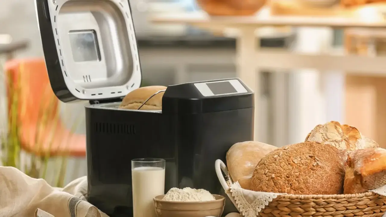 Machine à pain ouverte, avec du pain frais dans un panier. Avis sur la machine à pain : facile et pratique pour un pain maison.